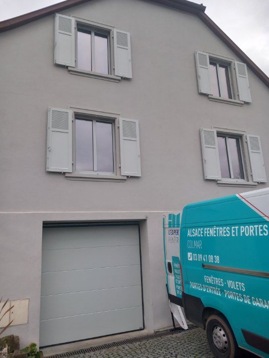 L'expert Fenêtre intervient pour la pose d'une fenêtre Fullsun.

Un camion l'expert Fenêtre est garé en marche arrière devant une maison blanche avec un garage fermé et 4 fenêtres.